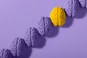 Row of purple brains with one bright yellow brain near the top for World Brain Health Day.